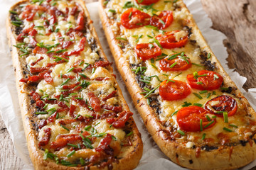Close-up pizza sandwiches with bacon, mushrooms, tomatoes and cheese on a parchment. horizontal