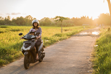 mom and child enjoy riding motorcycle scooter togehter © Odua Images