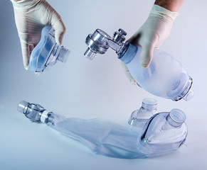 Hands hold resuscitator (ambu bag) and face mask. Isolated on white background