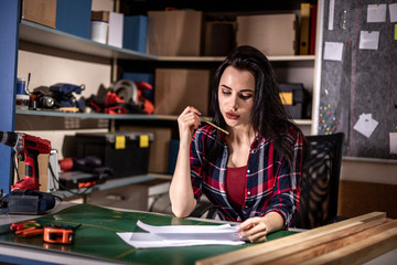 Craftsmen woman thinking an idea. Self employed female carpenter planning DIY project in her small business woodwork workshop