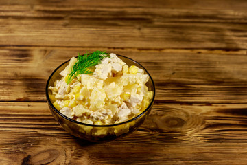 Festive salad with chicken breast, sweet corn, canned pineapple, cheese and mayonnaise on wooden table