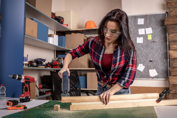 Home diy woman cutting plank of wood on workbench with saw renovating improving and decorating home
