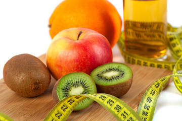 Apple, orange, kiwi with measure tape on white background