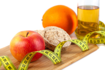 Apple, orange, kiwi with measure tape on white background