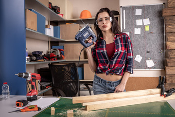 Home diy woman cutting plank of wood on workbench with saw renovating improving and decorating home