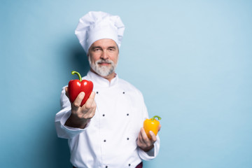 Food service, organic food, healthy diet, cooking and professional culinary concept - chef in white uniform holds vegetables.