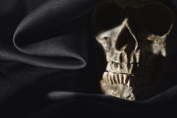 Closeup photo an old skull covered in black robe