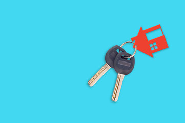 Two keys on metal ring and one red plastic house with window and door on blue table. Top view. Household concept. Copy space for your text