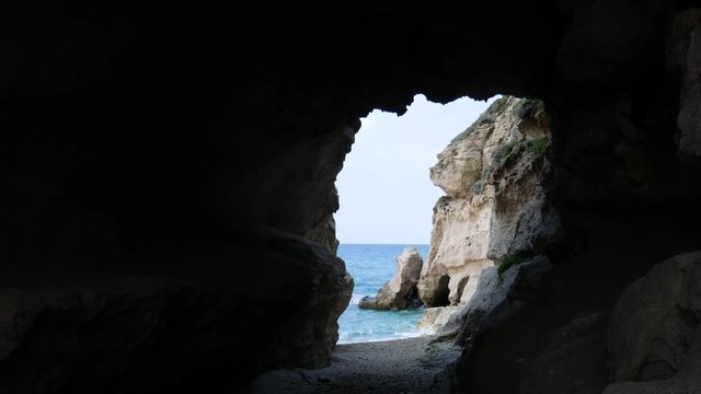 waves stand out on the rocky cliff on the sea at sunset. Calabrian emerald sea seen through a marine grotto (cave). Tropea, Calabria, Italy