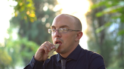 Adult Man Eating Healthy Organic Granola Bar in Park 