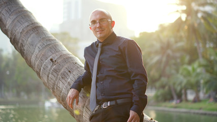 Dating Site Advertisement - Confident Handsome Man Leaning Against Palm Tree Smiling Into Camera 