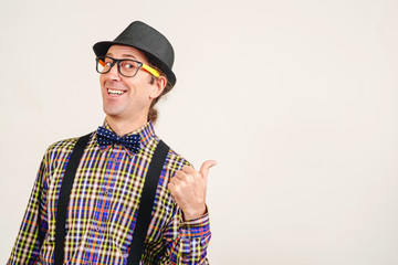 Funny man wearing retro clothes showing thumb up on white wall, copy space. Excited man in glasses shows like sign thumbs up and good like. Emotion and gesturing concept