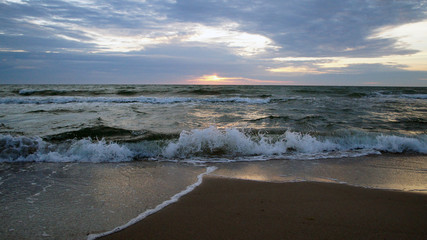 Summer evening sunny sunset in the sea on the shore. Sandy coast on the ocean.