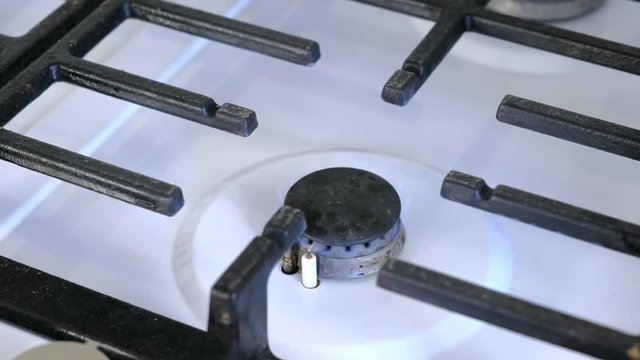 Self-igniting small gas berner lit and extinguished on gas sove. Gas stove with lattice. Close-up view.