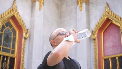 Importance of Drinking Enough Water on Vacation - Tourist Rehydrating While Exploring Asian Temple