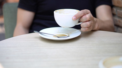 Young Caucasian Balding Man Drinking Coffee At Outdoor Cafe With People in Background