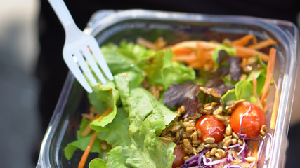 Putting Healthy Sunflower Seeds on Fresh Salad in Plastic Container