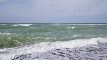 Fototapeta na wymiar Summer day sea turquoise waves hit the shore. Sandy coast of the ocean.