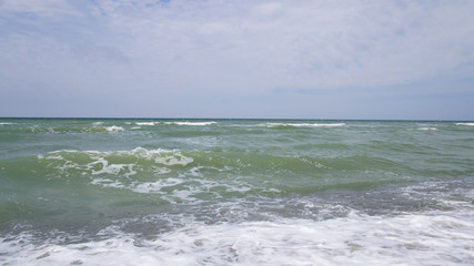 Summer day sea turquoise waves hit the shore. Sandy coast of the ocean.