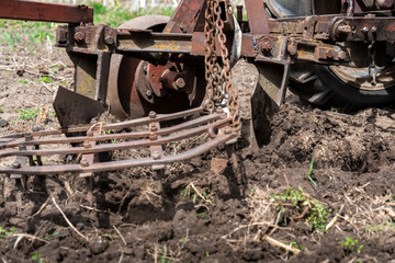 Fototapeta na wymiar old small tractor harrow field in spring, Caucasus. Karachay-Cherkessia Russia