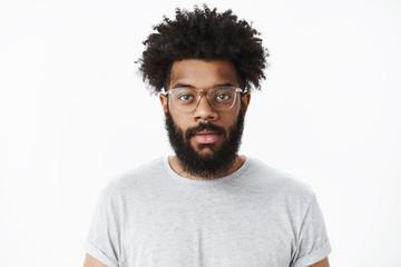 Close-up shot of attractive friendly-looking african american bearded man in glasses with pierced...