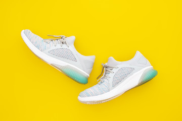 Pair of trendy sport sneakers on yellow background. Top view with copy space.