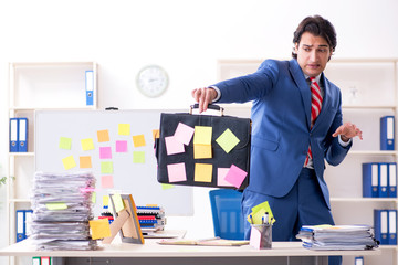 Young male handsome employee in conflicting priorities concept 