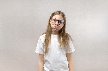 Funny blonde girl in glasses writhing her face, mimicking, having fun. Close-up.