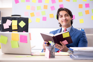 Young male handsome employee in conflicting priorities concept 