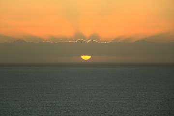 Naklejka premium Golden sunset light breaks through the sky with clouds over the ocean