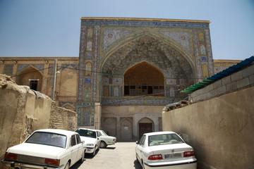 zaniedbany stary i zabytkowy budynek w mieście w iranie z zaparkowanymi przed nim białymi samochodami - obrazy, fototapety, plakaty