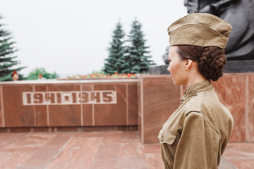 A girl in an old Soviet military uniform near the World War memorial. The celebration and...