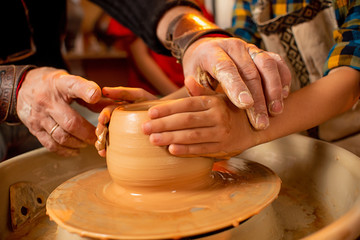 Children's hands work with clay on a special machine. Products from clay. Pottery