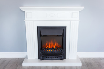 White wooden decorative electric fireplace with a beautiful burning flame. Interior photo on gray background. - 261520578