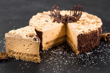 Sweet chocolate cake on the black wooden background