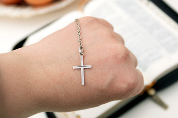 Woman holds silver cross in hand. Symbols christianity.