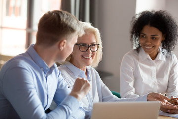 Smiling mature female mentor executive talking at diverse group meeting