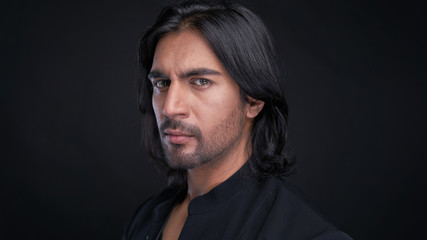 Fototapeta na wymiar Portrait of Indian man with long black hair in studio
