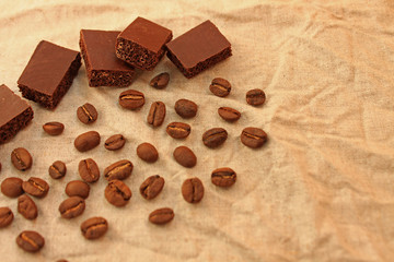 Chocolate cubes with colombian coffee beans on a linen texture background.