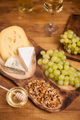 Top view of tasty walnuts next to fresh grapes on wooden plate