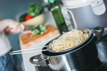 Pasta spaghetti in pan on the background of cooking woman