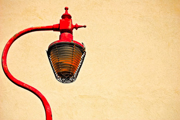 Obraz premium Rusty cast iron street lamp against cream painted textured wall