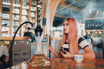 Young beautiful female smoking hookah. Smoke shisha hookah concept.