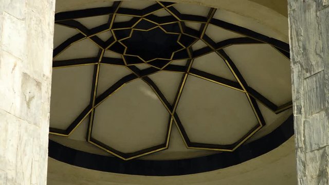 A steady, low angle, extreme close up shot of the cupola of a tower, with its symmetric, detailed pattern.