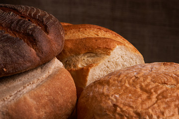 Different bread and wheat on the rustic table. Selective focus, close up