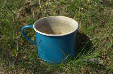 Obraz premium Old enamel metal battered mug grass garden