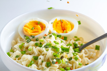 Instant noodles with vegetables and egg in plate. Noodles bowl on white background