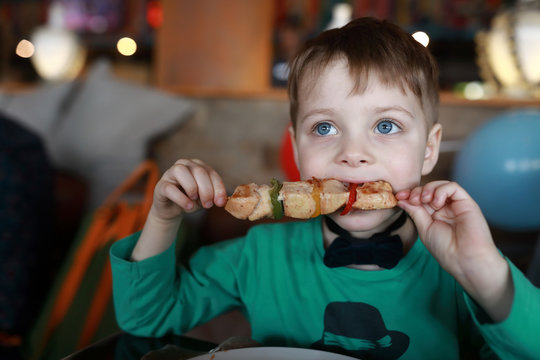 Child eating kebab on skewer