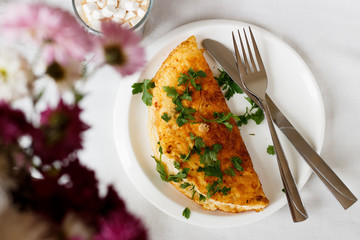 A photo of an omelette with parsley. White background with flowers