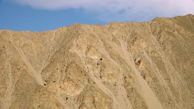 A panning, low angle, medium shot of yellow, carved argil hills in nature.